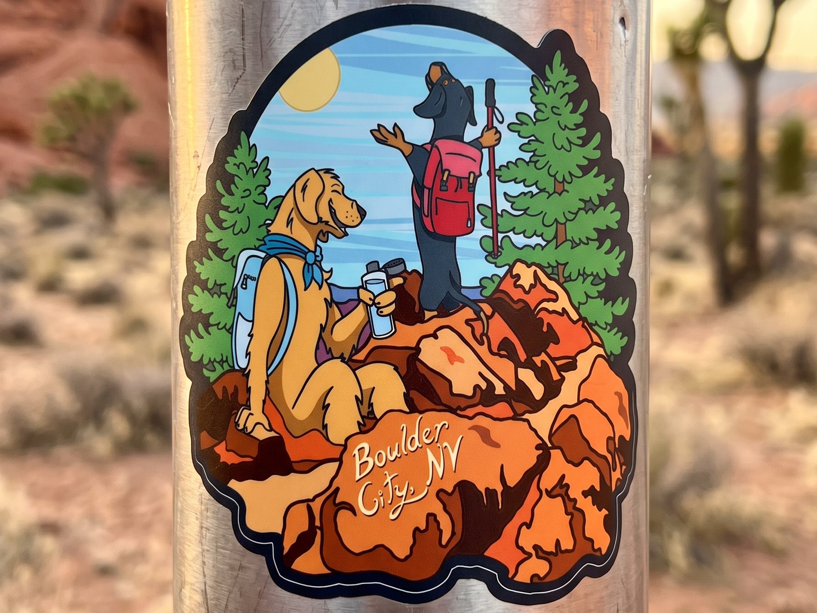 Custom vinyl sticker of two hiking dogs resting on red rocks for Boulder City, Nevada